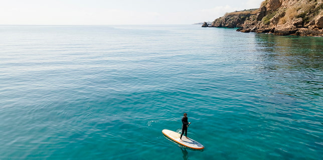Persona practicando paddle surf en aguas tranquilas