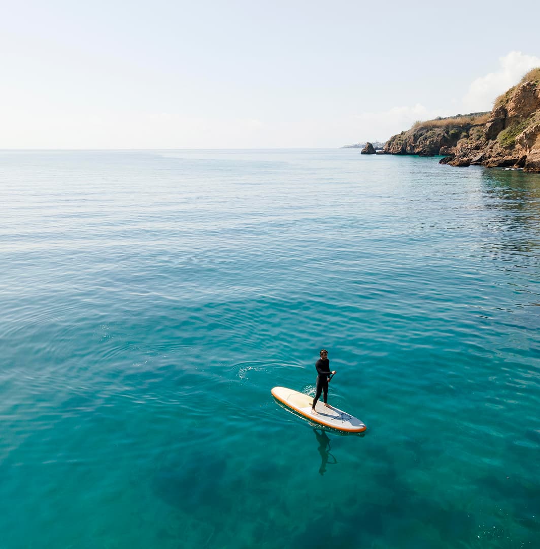 Persona practicando paddle surf en aguas tranquilas