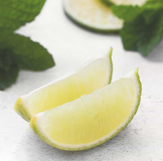 Ingredientes frescos Rodajas de lima y hojas de menta utilizadas para preparar mojitos.