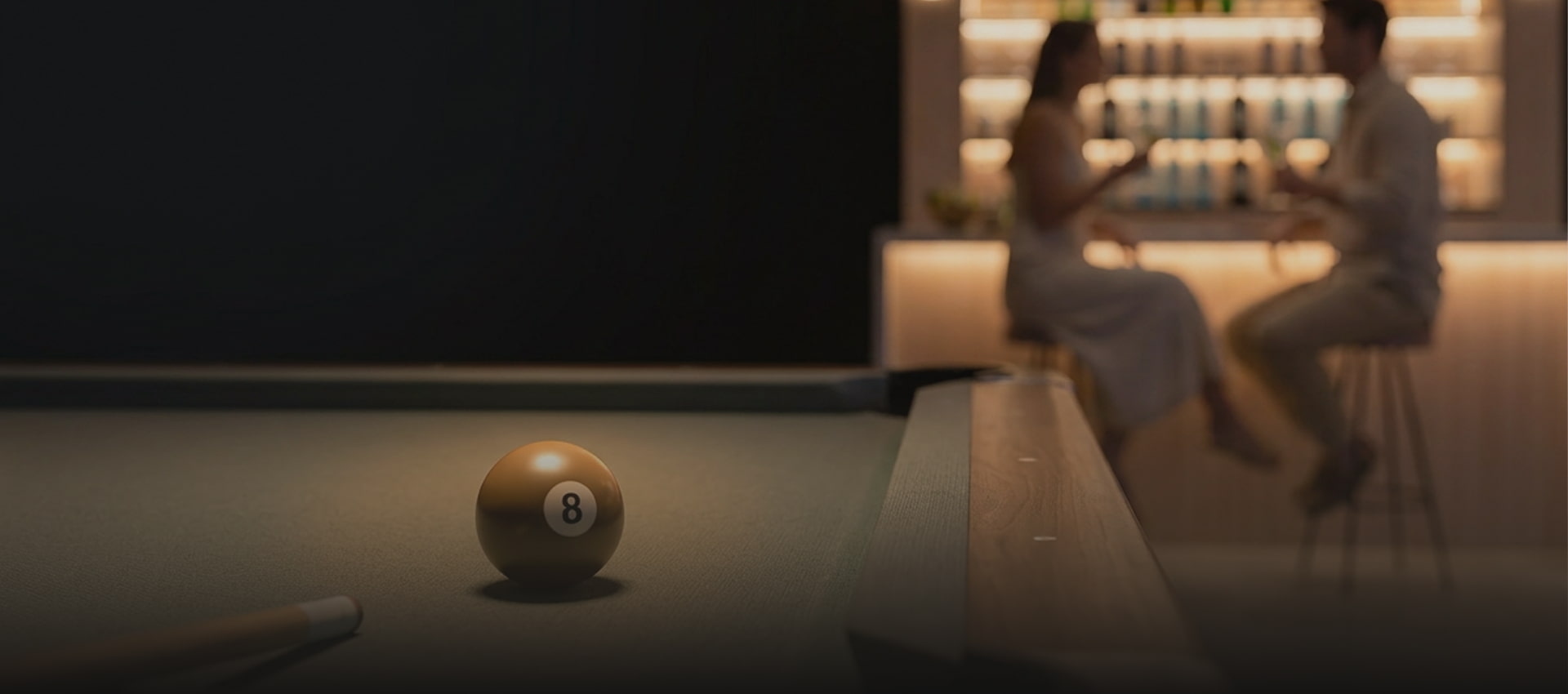 Entertainment room Pool table next to an illuminated bar.