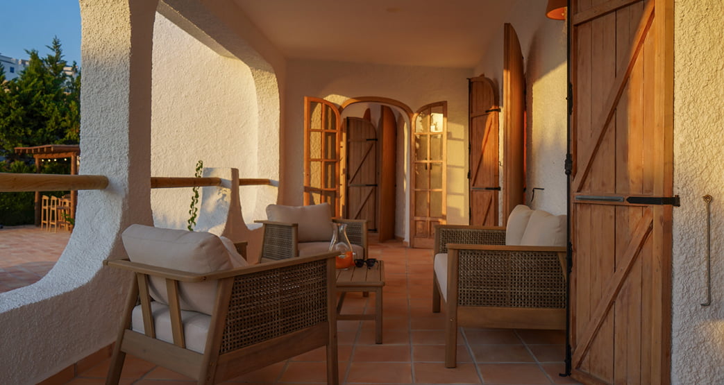 Terraza mediterránea con muebles de madera al atardecer.
