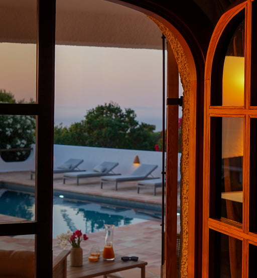 Puertas abiertas hacia una terraza con piscina al atardecer.