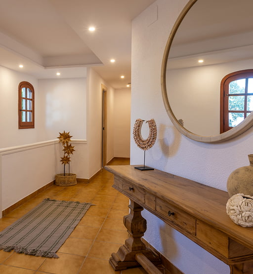 Mueble de madera y espejo redondo en un recibidor de estilo mediterráneo.
