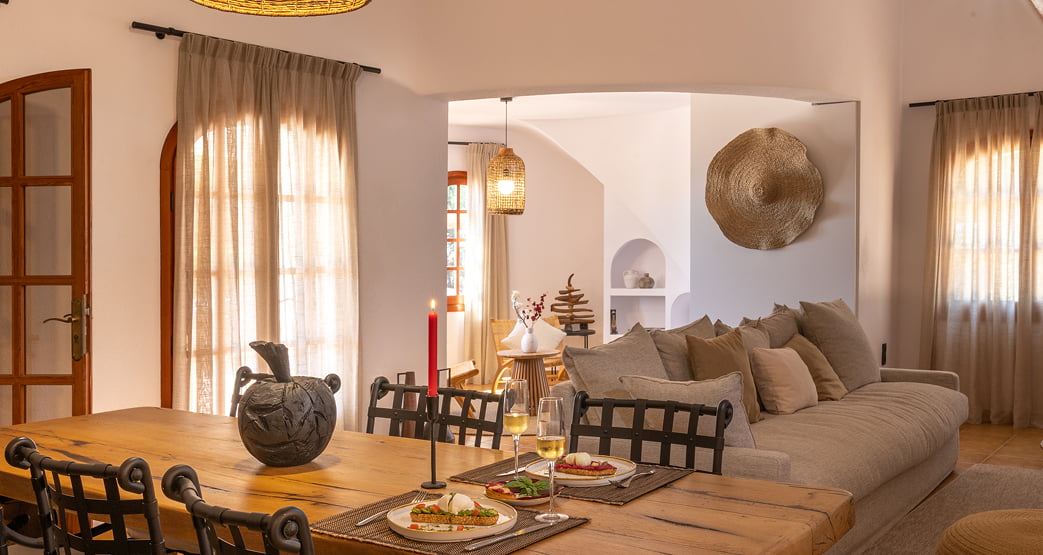 Salón comedor interior de estilo mediterráneo con mesa de madera y sofá.