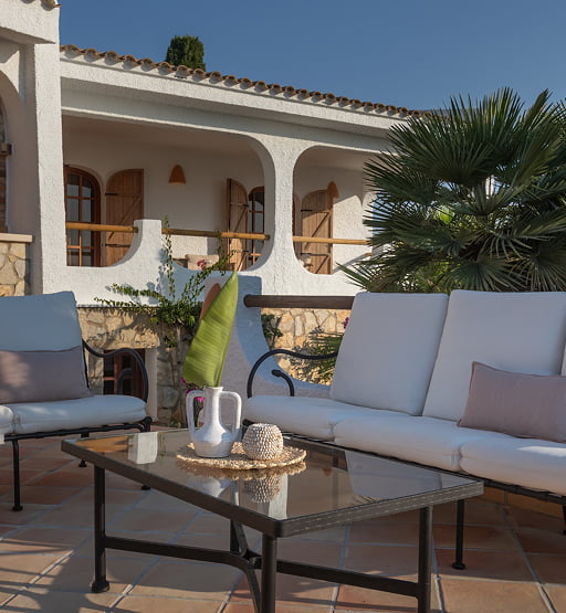 Sofás de exterior en una terraza con arcos y zona de barbacoa.