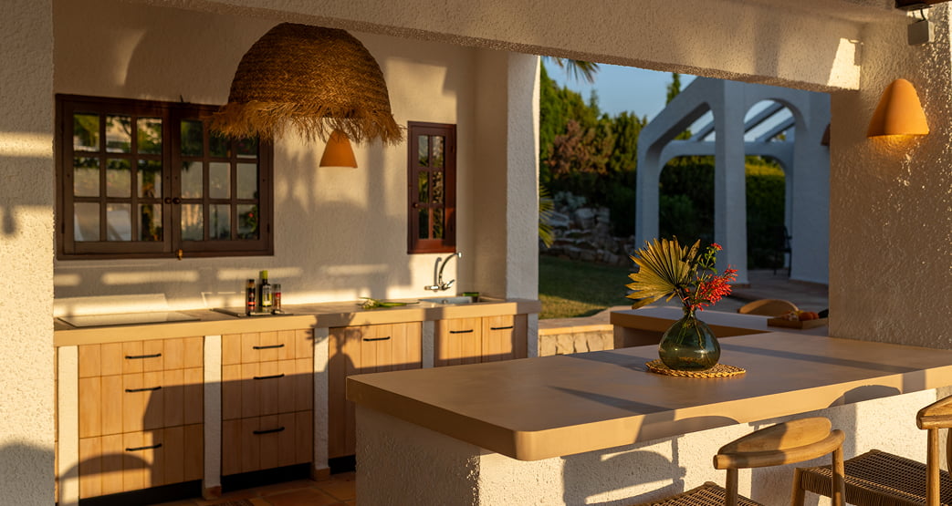 Cocina exterior y barra en una terraza mediterránea al atardecer.