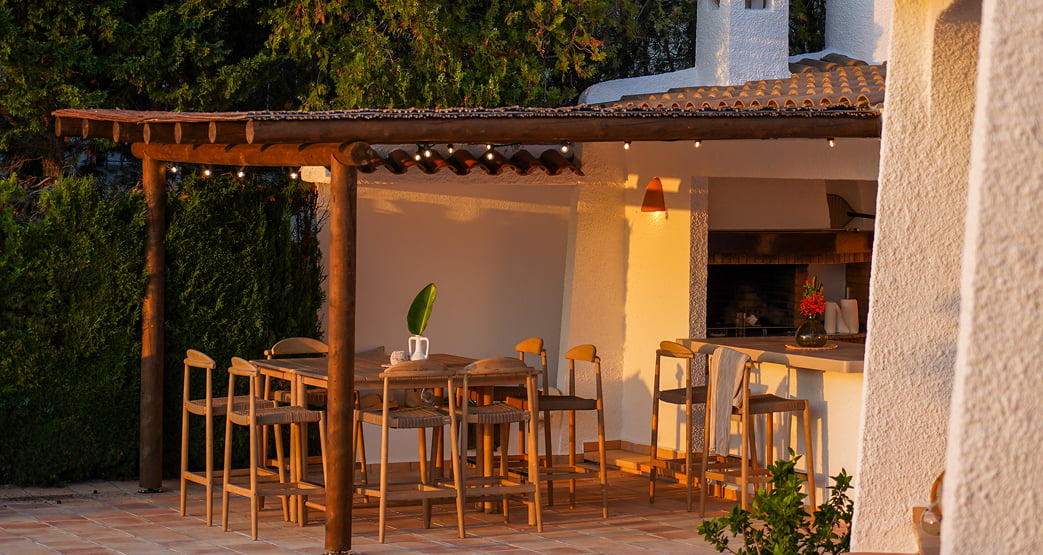 Mesa exterior junto a la barbacoa en una terraza al atardecer.