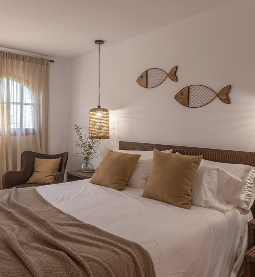 Cama doble y luces colgantes en una habitación decorada en tonos cálidos.