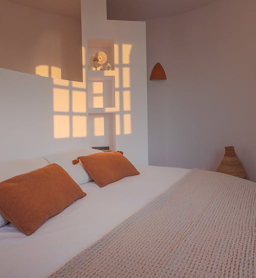 Cama doble iluminada por la luz del atardecer a través de la ventana.