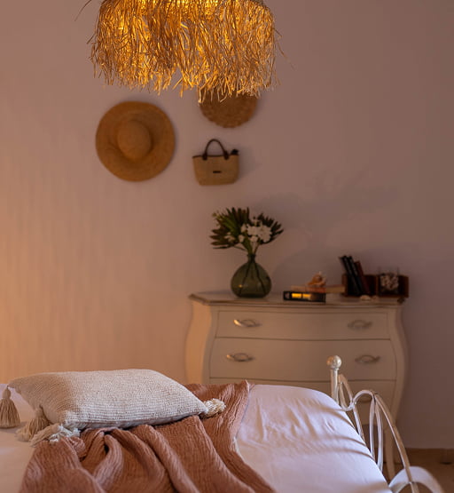 Cama doble y cómoda con decoración en un dormitorio con luz cálida.